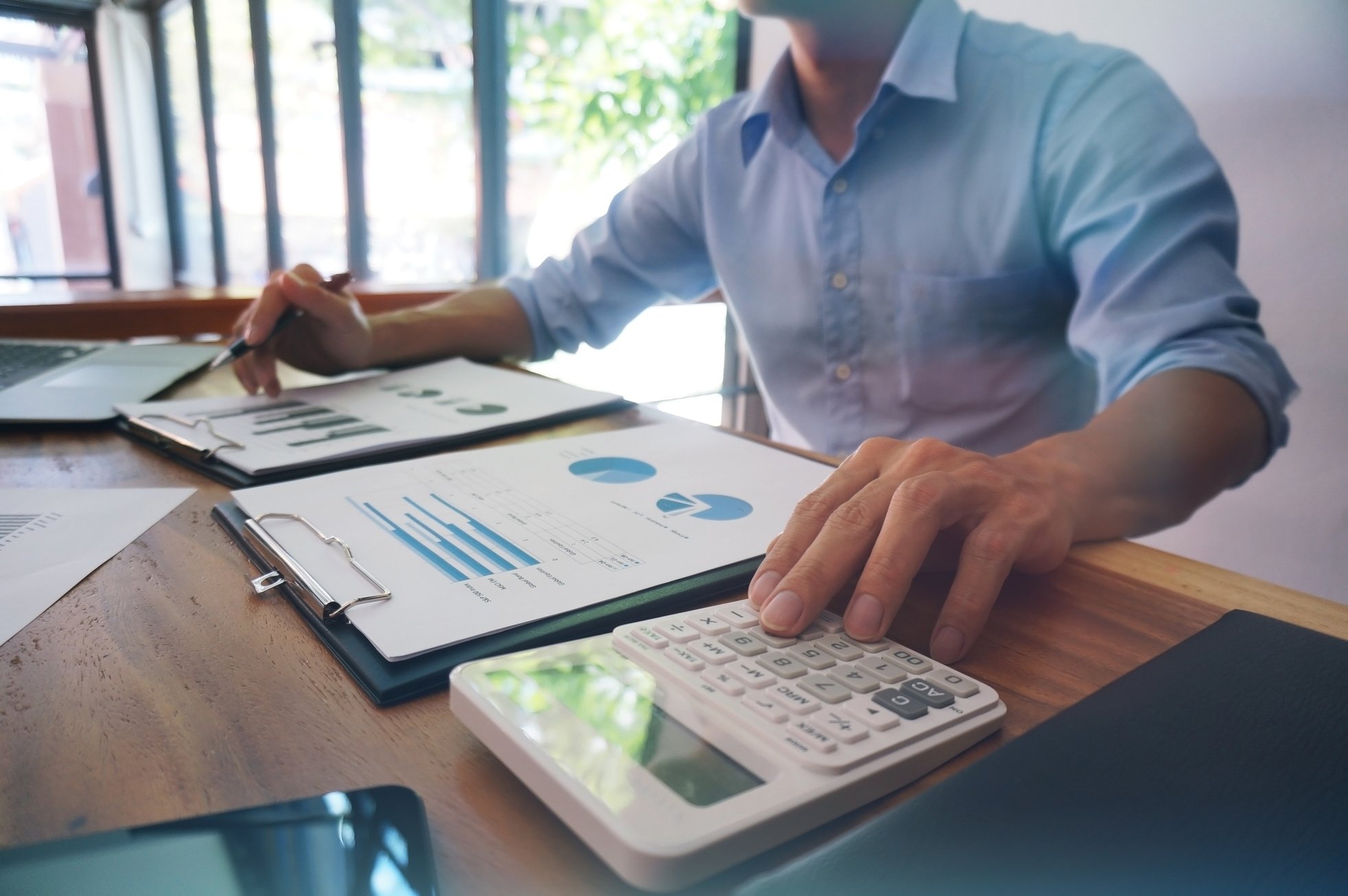 Businessman Analyzing Investment Charts and Pressing Calculator